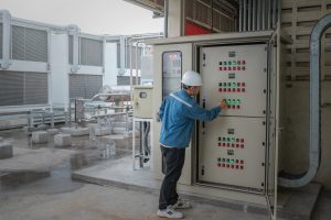 Young engineer checking temperature of refrigeration and setting temperature of compressor at control switchboard panel for test cool down of cold storage room in the factory
