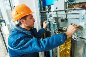 technician machinist worker at elevator mechanism installation or adjusting work of lift