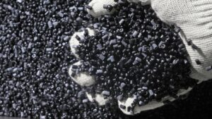 Plastic black gray granulated crumb. Manufacture of plastic water pipes of the factory. Process of making plastic tubes on the machine tool with the use of water and air pressure.