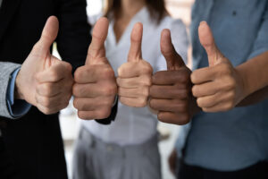 Close up view of diverse business team people hands showing thumbs up like finger gesture recommendation or good job choice. Professional multicultural team recommend corporate service.